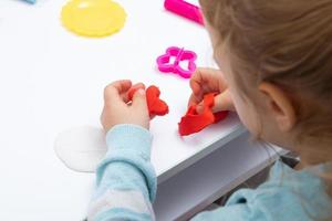 la fille à table joue avec de la pâte à modeler. jeux pour enfants pour la motricité fine photo