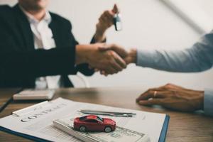 les acheteurs de voitures neuves et les vendeurs de voitures se serrent la main pour conclure des accords sur les ventes de voitures. photo