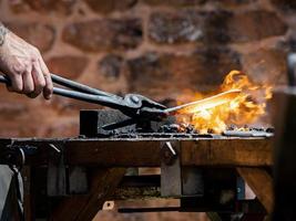 l'authentique forgeron forge le métal sur l'enclume. traditions médiévales photo