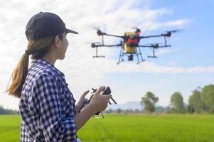 jeune agriculteur intelligent contrôlant la pulvérisation d'engrais et de pesticides par drone sur les terres agricoles, les innovations de haute technologie et l'agriculture intelligente photo