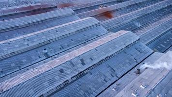 toits des bâtiments d'usine dans l'industrie lourde avec fumée blanche contre le ciel bleu au coucher du soleil. photo aérienne vue par drone du haut de la plante.