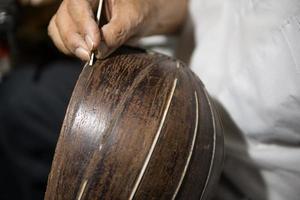 maître adulte restaure de vieux instruments de musique. Sculpture sur bois photo