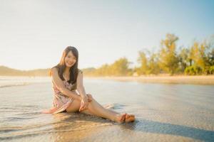 jeune femme asiatique se sentant heureuse sur la plage, belle femme heureuse se détendre souriant amusant sur la plage près de la mer au coucher du soleil le soir. les femmes de style de vie voyagent sur le concept de plage. photo