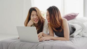 belles jeunes femmes asiatiques lgbt couple heureux lesbien assis sur le lit câlin et utilisant un ordinateur portable ensemble chambre à coucher à la maison. couple de lesbiennes lgbt ensemble concept à l'intérieur. passer du bon temps à la maison. photo