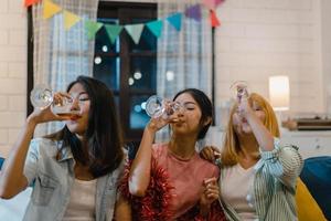 groupe de femmes asiatiques faisant la fête à la maison, femme buvant un cocktail parlant en s'amusant ensemble sur un canapé dans le salon la nuit. adolescent jeune ami jouer au jeu, amitié, célébrer le concept de vacances. photo