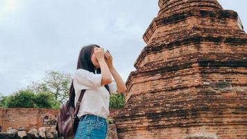 femme asiatique voyageuse utilisant un appareil photo pour prendre une photo tout en passant des vacances à ayutthaya, en thaïlande, une touriste japonaise profite de son voyage dans un site étonnant de la ville traditionnelle.