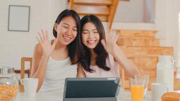 les lesbiennes asiatiques influenceuses lgbtq couplent des femmes vlog à la maison, de jeunes filles amatrices d'asie heureuses d'utiliser une tablette enregistrent une vidéo vlog dans les médias sociaux tout en prenant leur petit déjeuner dans la cuisine à la maison le matin concept. photo