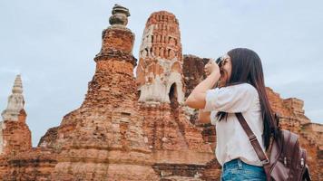 femme asiatique voyageuse utilisant un appareil photo pour prendre une photo tout en passant des vacances à ayutthaya, en thaïlande, une touriste japonaise profite de son voyage dans un site étonnant de la ville traditionnelle.