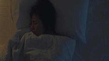 jeune femme asiatique nerveuse faisant un cauchemar allongée sur son lit dans sa chambre à la maison au milieu de la nuit. souffrant de maux de tête ou de migraine, d'insomnie, d'apnée du sommeil ou de concept de stress. vue de dessus. photo