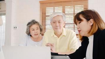 asia smart female agent propose une assurance santé pour les couples âgés par document, tablette et ordinateur portable. couple asiatique âgé consultant avec un agent d'assurance tout en étant assis à la maison. photo