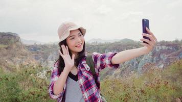 routard asiatique femme selfie au sommet de la montagne, jeune femme heureuse utilisant un téléphone portable prenant selfie profiter de vacances en randonnée aventure. les femmes de style de vie voyagent et se détendent. photo