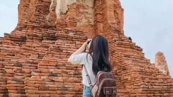 femme asiatique voyageuse utilisant un appareil photo pour prendre une photo tout en passant des vacances à ayutthaya, en thaïlande, une touriste japonaise profite de son voyage dans un site étonnant de la ville traditionnelle.