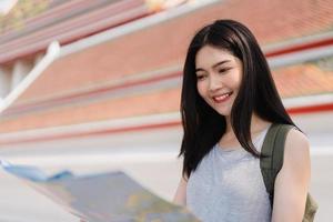 voyageur femme asiatique direction sur la carte de localisation à bangkok, thaïlande, routard femme regardant sur la carte trouver un point de repère tout en passant des vacances. les femmes de style de vie voyagent dans le concept de ville d'asie. photo