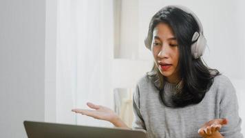 une femme d'affaires d'asie porte un casque à l'aide d'un ordinateur portable parle à des collègues du plan d'appel vidéo tout en travaillant intelligemment à domicile dans la chambre. auto-isolement, distanciation sociale, quarantaine pour le virus corona. photo