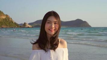 jeune femme asiatique marchant sur la plage. belle femme heureuse se détendre en marchant sur la plage près de la mer au coucher du soleil en soirée. les femmes de style de vie voyagent sur le concept de plage. photo