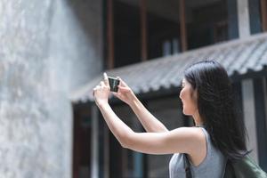 femme asiatique voyageuse utilisant un téléphone portable pour prendre une photo tout en passant des vacances à pékin, en chine, une femme profite d'un voyage dans un point de repère incroyable de la ville. les femmes de style de vie voyagent dans le concept de ville.