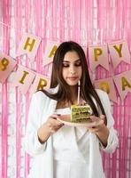 belle femme excitée célébrant son anniversaire tenant un gâteau faisant un vœu photo