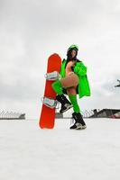 belle jeune femme posant avec un snowboard sur une piste de ski photo