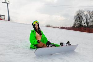 belle jeune femme posant avec un snowboard sur une piste de ski photo