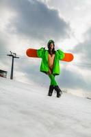 belle jeune femme posant avec un snowboard sur une piste de ski photo