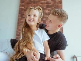 Frères et sœurs de race blanche - adolescent garçon frère et petite fille soeur jouant dans des avions à l'intérieur d'un loft moderne sur fond de ciment gris photo