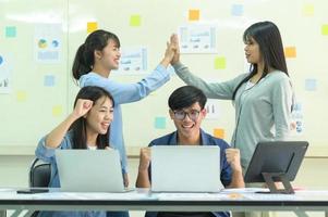 équipe de jeunes acclamant avec ordinateur portable et tablette. photo