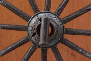 détail de la roue de chariot en bois, roues de charrette rapprochées du centre, ancienne roue de chariot en bois oubliée appuyée contre un mur en bois. roues de charrette au vieux mur de bois. photo