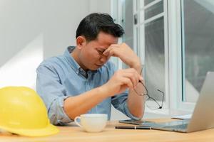 un ingénieur masculin assis au bureau souffre de fatigue oculaire. photo