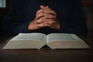 l'homme lit et prie l'Écriture ou la sainte bible sur une table en bois avec espace de copie. religion, croire concept. photo