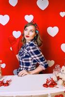 belle jeune femme dans un style pin-up sur fond rouge avec des coeurs blancs photo