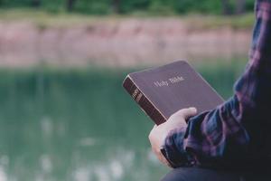 homme tenant la sainte bible prête à être lue et ayant une relation avec la foi de dieu, la spiritualité et la religion concept chrétien. photo