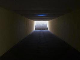 passage pour piétons souterrain jaune vide. tunnel et lumière du jour au bout. marches vers le haut au passage pour piétons. un long tunnel en béton avec des lanternes dans le sous-sol de la ville. photo