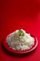 riz basmati blanc ordinaire cuit dans une assiette rouge sur fond rouge photo