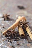 bâtons de cannelle, étoiles d'anis et grains de poivre noir sur fond texturé photo