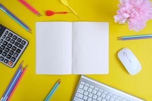 un cahier vierge avec un stylo se trouve au-dessus d'une table de bureau bleue avec des outils et des fournitures informatiques. vue de dessus avec espace de copie, mise à plat. photo