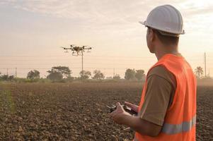 ingénieur masculin contrôlant la pulvérisation d'engrais et de pesticides par drone sur les terres agricoles, les innovations de haute technologie et l'agriculture intelligente photo