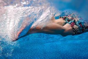 les jambes des hommes nageant sous l'eau dans la piscine en été photo