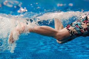 les jambes des hommes dans les escaliers sous l'eau dans la piscine en été photo