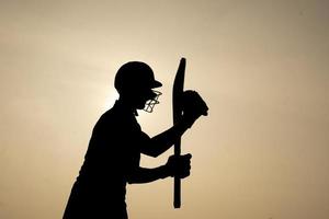 silhouette d'un joueur de cricket célébrant après avoir obtenu un siècle dans le match de cricket. joueurs de cricket indiens et concept sportif. photo