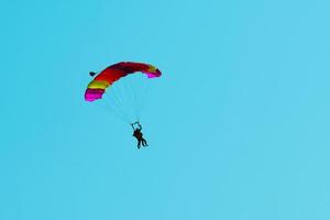 saut en parachute tandem. silhouette de parachutiste volant dans un ciel bleu clair. photo