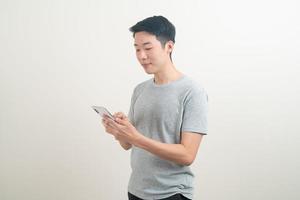 jeune homme asiatique utilisant ou parlant un smartphone et un téléphone portable photo