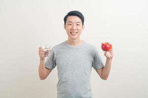 jeune homme asiatique avec un verre d'eau et une pomme à portée de main photo