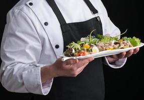 le chef en uniforme sert un plat dans une assiette photo