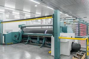 le fil textile sur la machine d'emballage est vissé sur le grand arbre. machines et équipements dans une usine textile photo