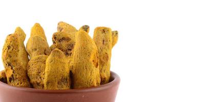 Racines de curcuma sèches ou écorces dans un pot en argile isolé sur fond blanc photo