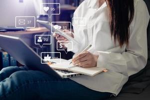 concept d'écran d'icônes virtuelles de médias sociaux et de marketing. gros plan d'une femme d'affaires tapant du clavier avec un ordinateur portable et une tablette photo