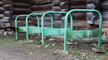 Le parking à vélos en métal est peint en vert sans vélo, à la campagne près d'une maison en bois. espace de stockage pour les véhicules à deux roues. photo