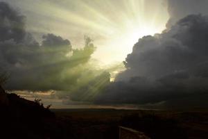 image cloudscape de nuages orageux sombres dans le ciel bleu avec rayon de soleil. les rayons du soleil après la pluie. paysage où les rayons du soleil filtrent à travers les nuages gris. ciel dramatique alors que le soleil se cache photo