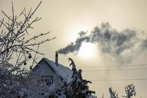 la fumée de la cheminée sur le toit de la maison. la maison est chauffée en hiver. saison de chauffe. photo