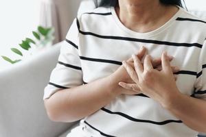 gros plan d'une femme asiatique ayant une crise cardiaque. femme touchant le sein et ayant des douleurs thoraciques. concept de soins de santé et médical. photo